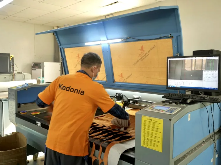 Factory operator cutting unstuffed plush fabric panels on production equipment