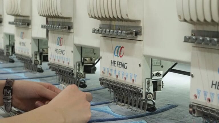 Multi-head embroidery machine stitching plush face details on flat fabric panels